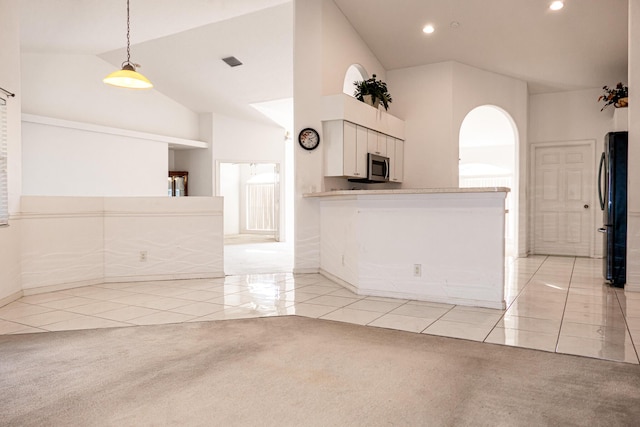 kitchen with white cabinets, light carpet, decorative light fixtures, and fridge