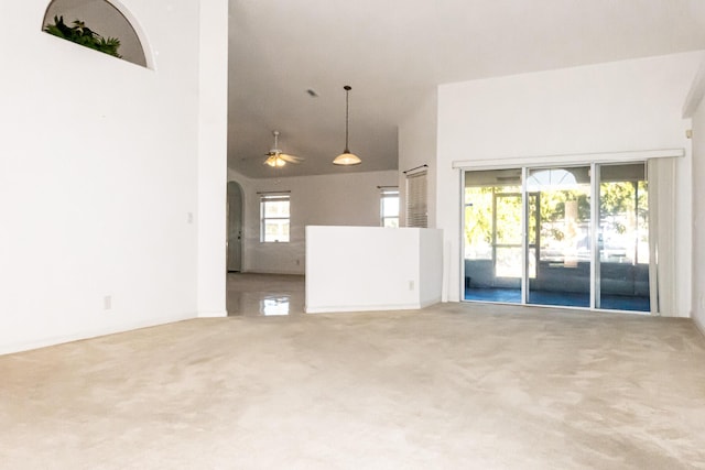 unfurnished living room featuring carpet flooring, ceiling fan, and a healthy amount of sunlight