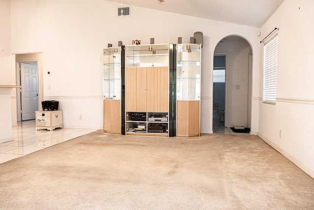 unfurnished living room featuring light colored carpet and vaulted ceiling