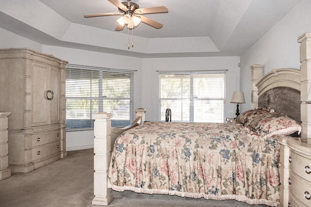 bedroom with ceiling fan, a raised ceiling, and light colored carpet