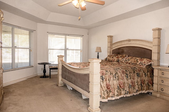 bedroom featuring a raised ceiling, ceiling fan, and light colored carpet