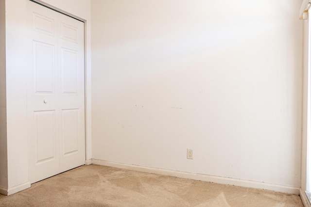 unfurnished bedroom featuring light colored carpet and a closet