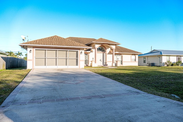 view of front of home featuring a front yard, central AC, and a garage