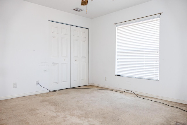 unfurnished bedroom with ceiling fan, light carpet, and a closet