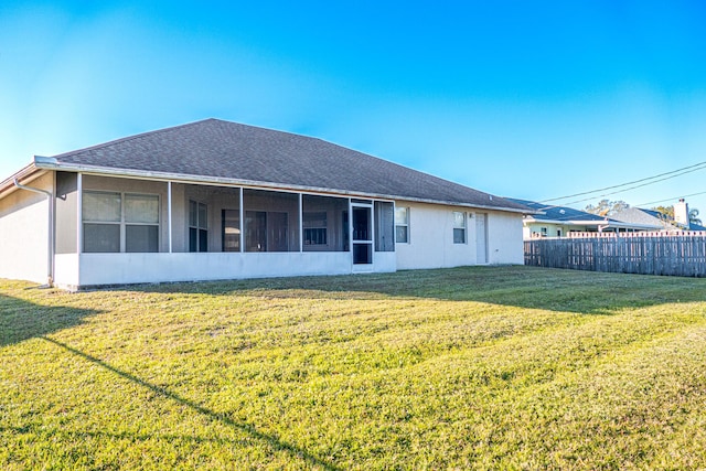 rear view of house featuring a sunroom and a yard