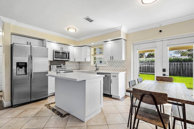 kitchen with light countertops, stainless steel appliances, visible vents, decorative backsplash, and a healthy amount of sunlight