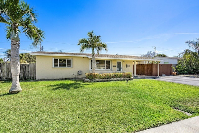 ranch-style home featuring driveway, a front yard, an attached carport, stucco siding, and fence