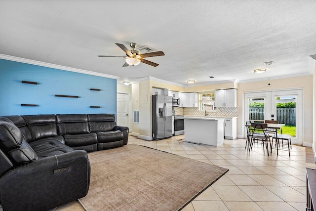 living room with light tile patterned floors, visible vents, ornamental molding, and ceiling fan