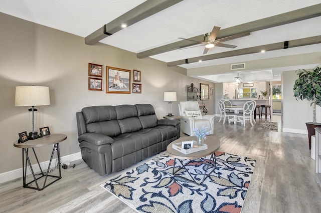 living room with hardwood / wood-style floors, ceiling fan, and beam ceiling