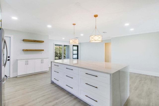 kitchen featuring a kitchen island, pendant lighting, white cabinetry, light stone countertops, and light wood-type flooring