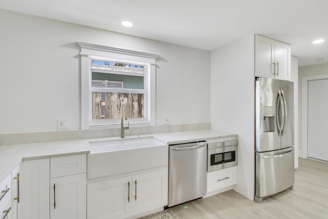 kitchen featuring white cabinetry, sink, light hardwood / wood-style flooring, and appliances with stainless steel finishes