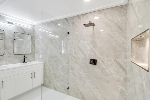 bathroom featuring a tile shower, vanity, and tile walls