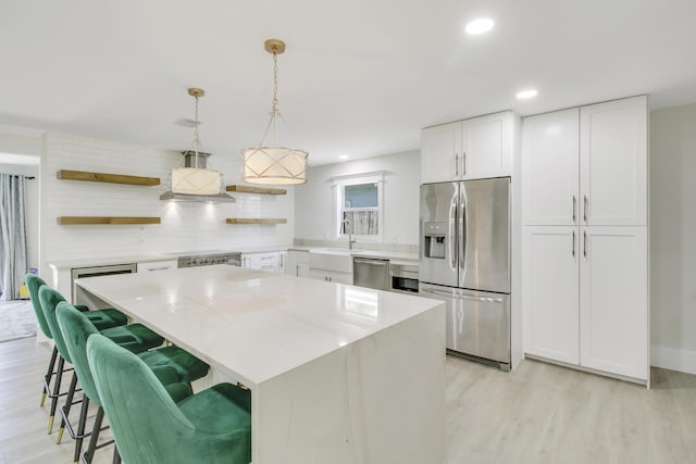 kitchen with a breakfast bar, white cabinetry, hanging light fixtures, a kitchen island, and stainless steel appliances