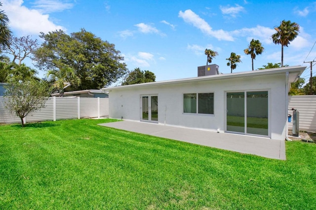 back of property with cooling unit, a lawn, and a patio area