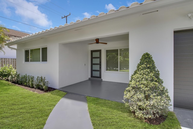 entrance to property with a yard and ceiling fan