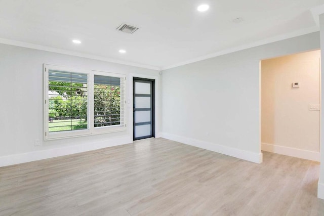 empty room featuring light wood-type flooring and ornamental molding