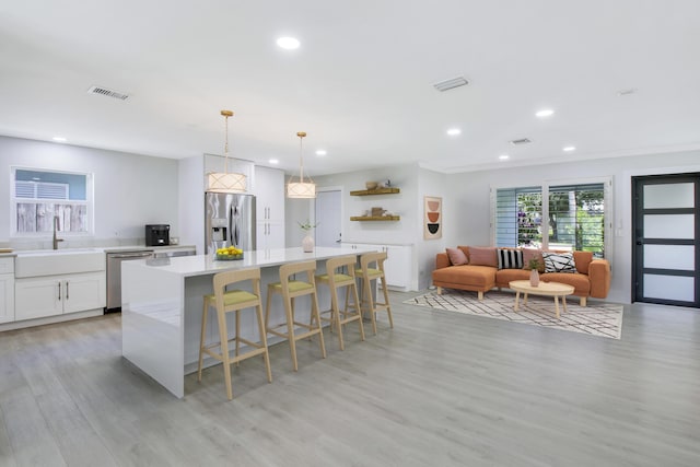 kitchen featuring appliances with stainless steel finishes, sink, white cabinets, hanging light fixtures, and a large island