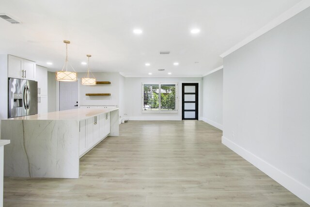 kitchen featuring light stone countertops, pendant lighting, light hardwood / wood-style flooring, white cabinets, and a kitchen island