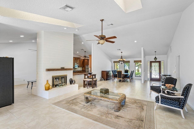 living room featuring a textured ceiling, light tile patterned floors, high vaulted ceiling, a fireplace, and ceiling fan