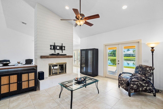 tiled living room with a water view, ceiling fan, french doors, high vaulted ceiling, and a textured ceiling