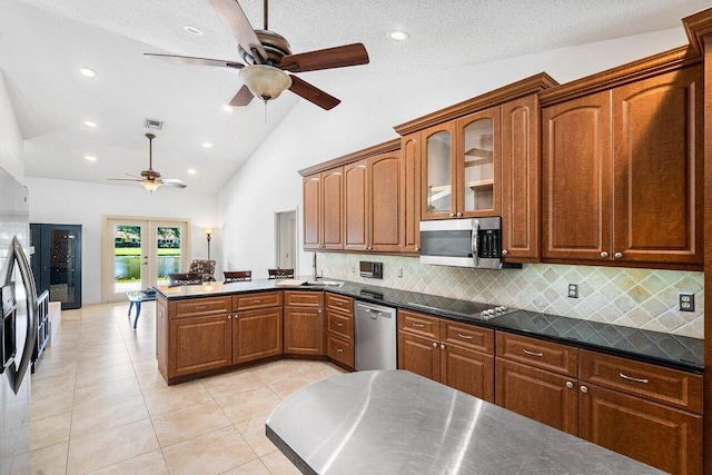 kitchen featuring stainless steel appliances, french doors, dark stone countertops, tasteful backsplash, and light tile patterned floors