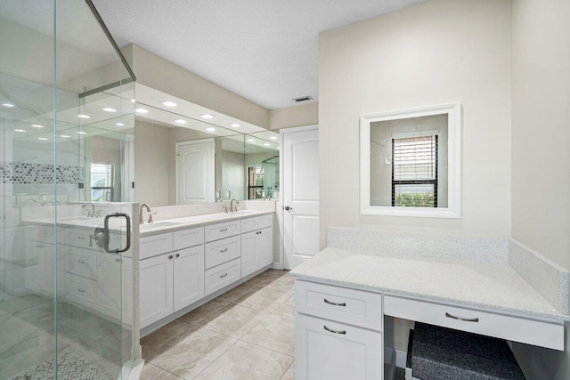 bathroom with a textured ceiling, tile patterned floors, an enclosed shower, and vanity