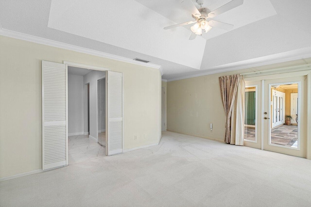 carpeted spare room with a raised ceiling, ceiling fan, ornamental molding, and french doors