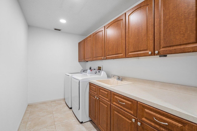 clothes washing area with cabinets, independent washer and dryer, light tile patterned floors, a textured ceiling, and sink