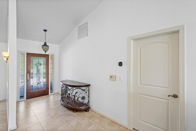 tiled foyer entrance with lofted ceiling and a textured ceiling