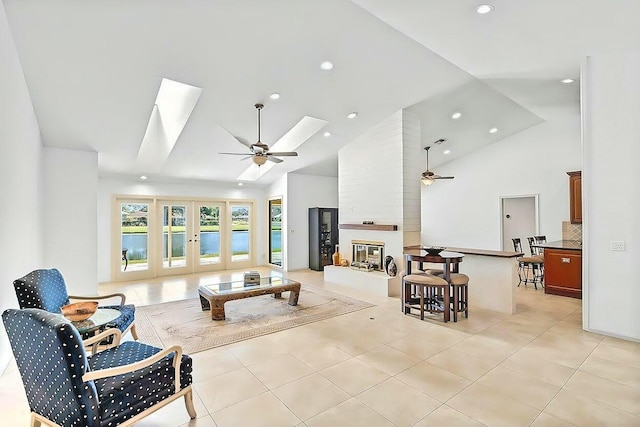 living room featuring a large fireplace, ceiling fan, french doors, and a skylight