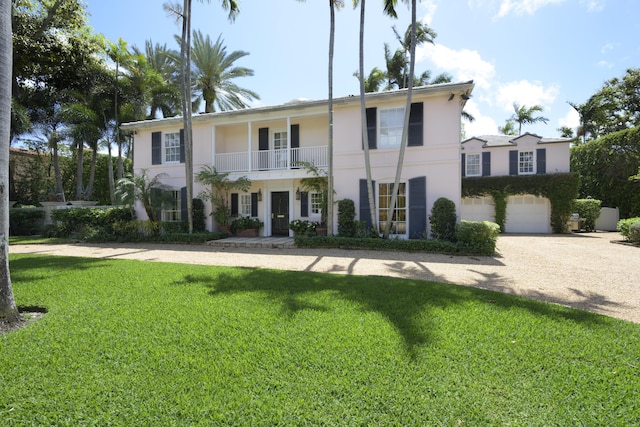 view of front of property with a balcony, a front lawn, and a garage