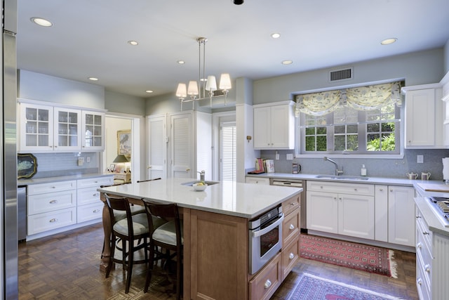 kitchen with backsplash, a kitchen island, sink, white cabinetry, and oven