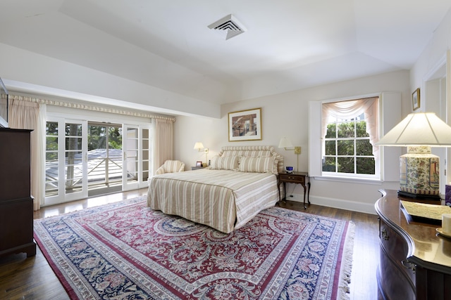 bedroom featuring access to outside, a tray ceiling, and dark wood-type flooring