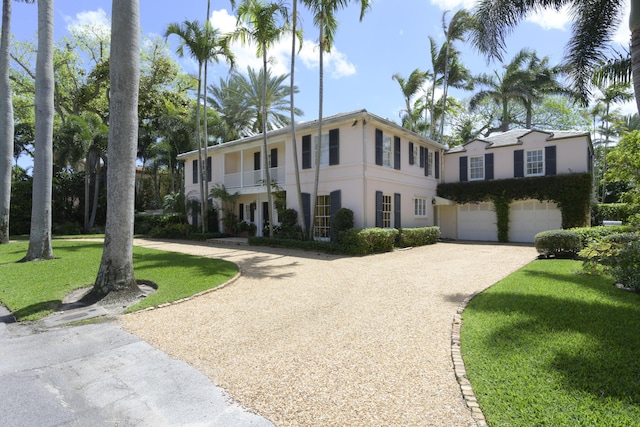 view of front facade with a garage, a balcony, and a front lawn