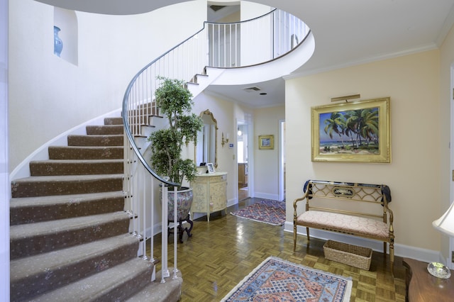 foyer entrance featuring dark parquet flooring, a towering ceiling, and ornamental molding