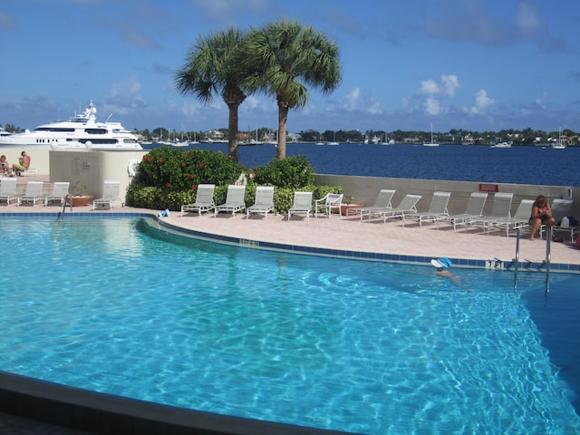 view of pool with a water view and a patio