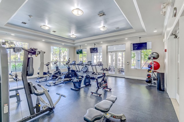 exercise room featuring a raised ceiling, ornamental molding, and french doors