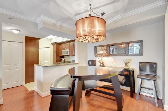 dining room with sink, light hardwood / wood-style flooring, crown molding, and a notable chandelier