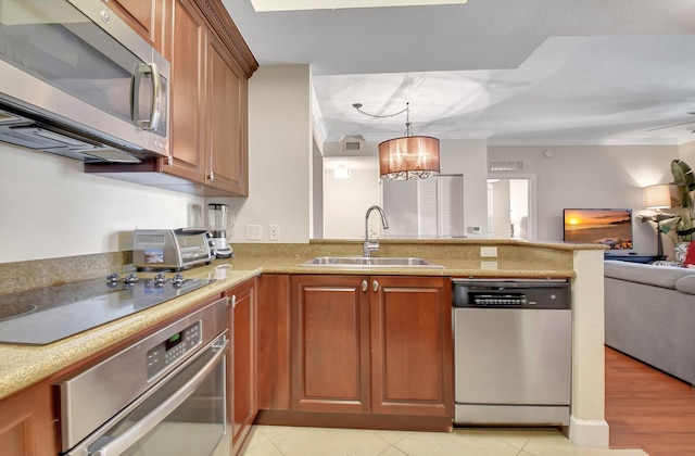 kitchen featuring stainless steel appliances, hanging light fixtures, crown molding, and sink