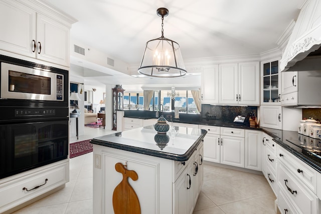 kitchen featuring white cabinets, black appliances, pendant lighting, a chandelier, and a center island