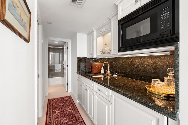 kitchen featuring backsplash, white cabinets, sink, light tile patterned floors, and black microwave