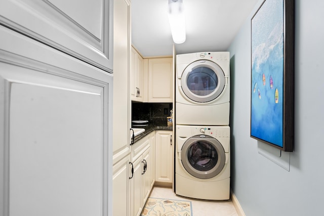 washroom with cabinets, light tile patterned floors, and stacked washer and dryer