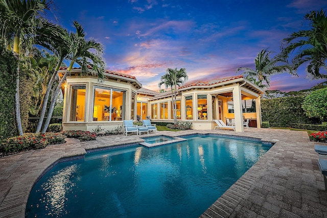 pool at dusk with an in ground hot tub, ceiling fan, and a patio