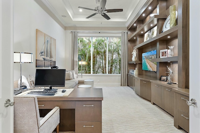 office area featuring ceiling fan, ornamental molding, a tray ceiling, and light carpet