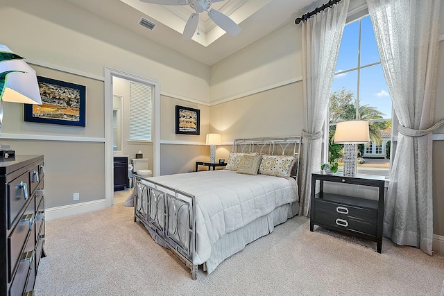 bedroom featuring connected bathroom, light colored carpet, and ceiling fan