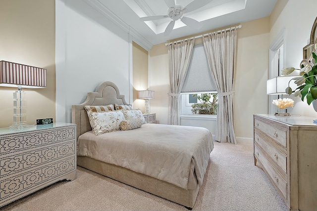 bedroom with ceiling fan, a tray ceiling, and light carpet