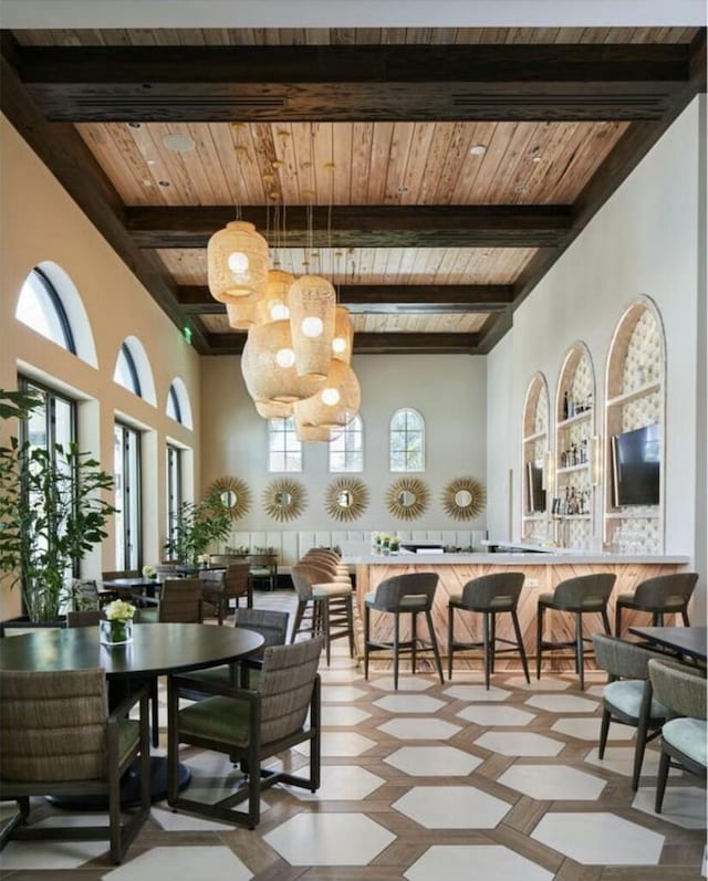 dining room featuring beamed ceiling, a healthy amount of sunlight, and wooden ceiling