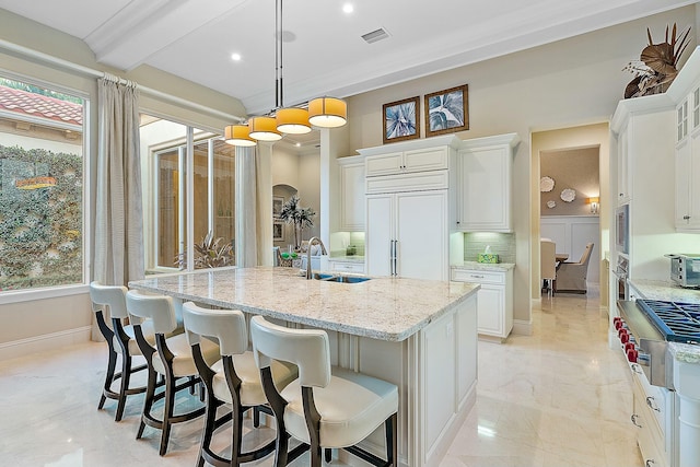 kitchen featuring pendant lighting, a kitchen island with sink, and white cabinets