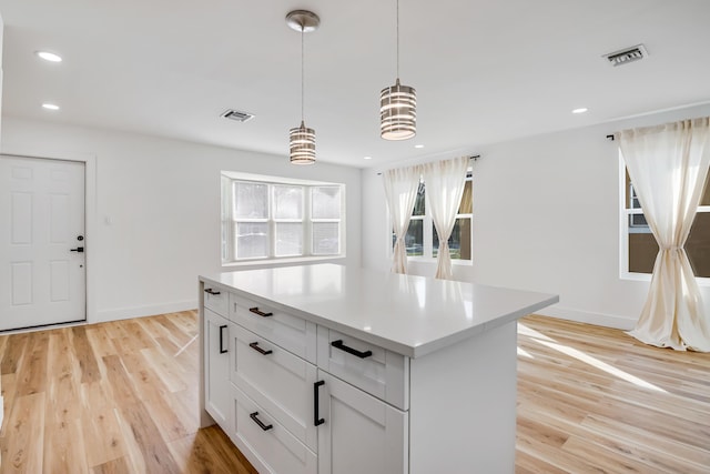 kitchen featuring white cabinetry, a kitchen island, pendant lighting, and light wood-type flooring