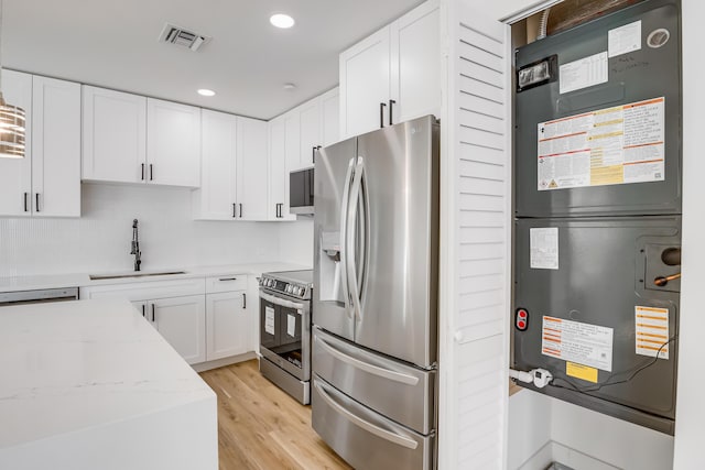 kitchen with white cabinetry, sink, stainless steel appliances, light stone counters, and light hardwood / wood-style floors